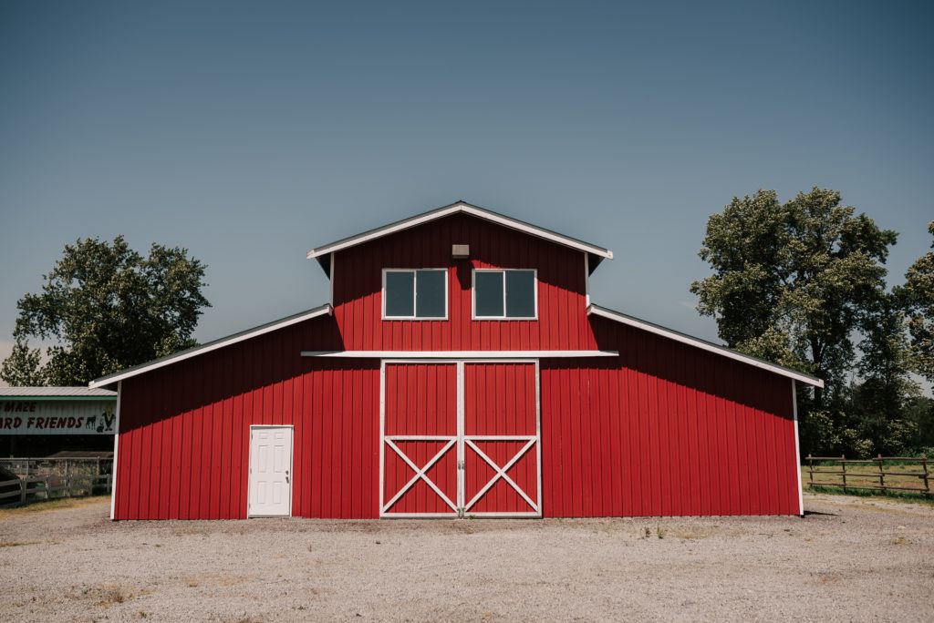 The Hopcott Farms classic big red barn with white trim and barn doors