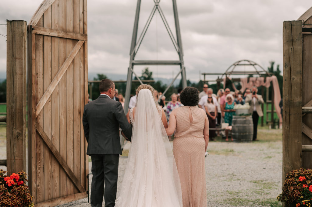 Rustic barn doors open for a bride and her parents revealing the open air wedding ceremony space at Hopcott Farms