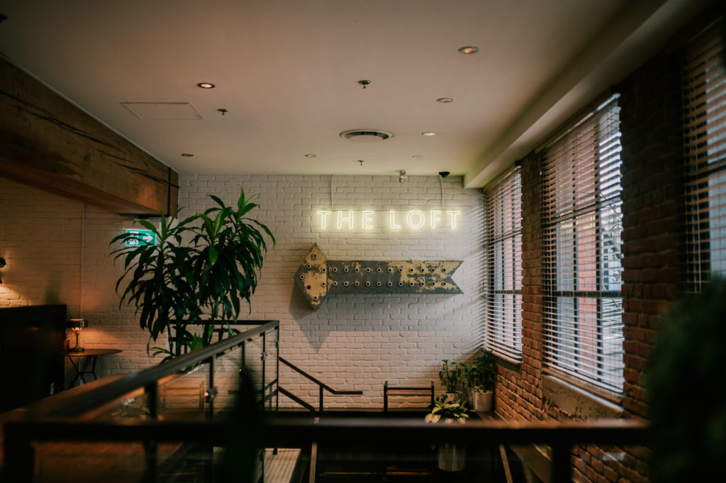 A view of The Loft at Earls Yaletown entrance with neon sign and antique style arrow feature