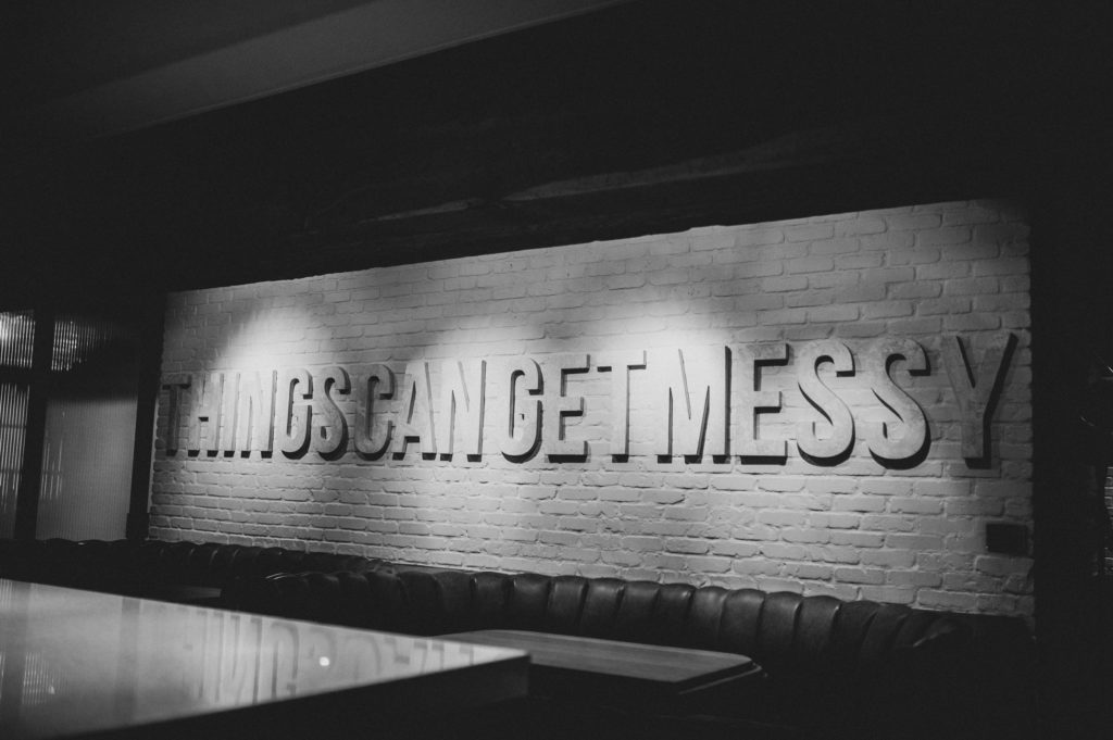 Sign "Things Can Get Messy" against white brick wall